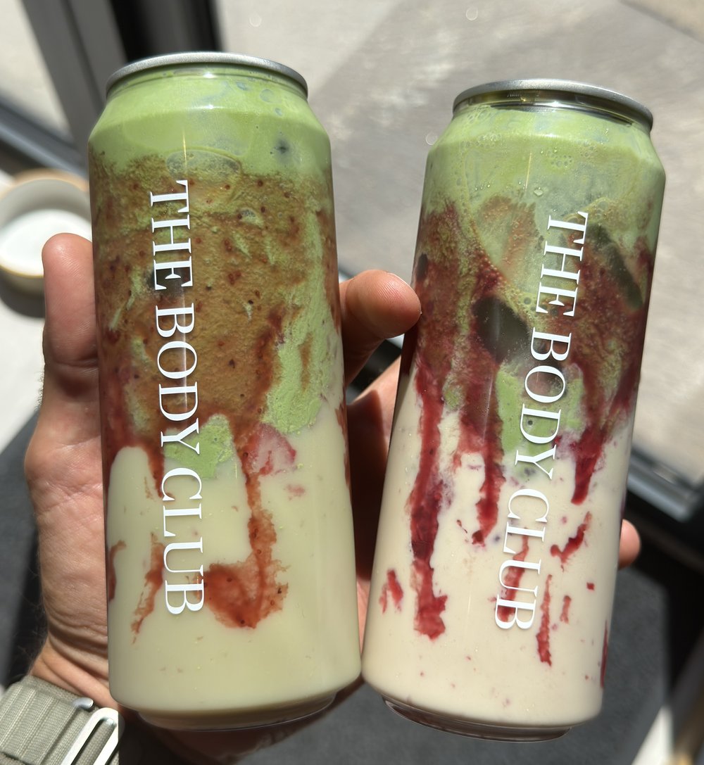 Canettes personnalisées THE BODY CLUB tenues en main, boissons smoothie